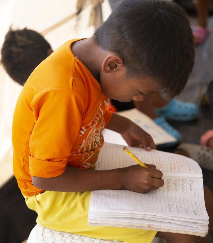 Child writing in temporary learning centre Maicao settlement