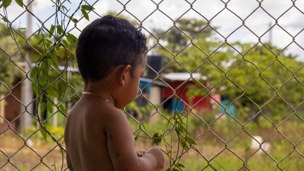 Niño mirando por la rejas del colegio